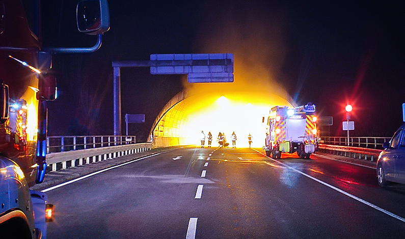 Feuerwehrleute suchen mit Stöcken den verrauchten Tunnel ab