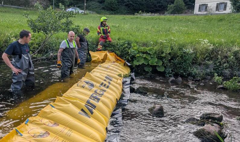 Feuerwehrleute stehen neben fertig aufgebauten Watergate im Bach